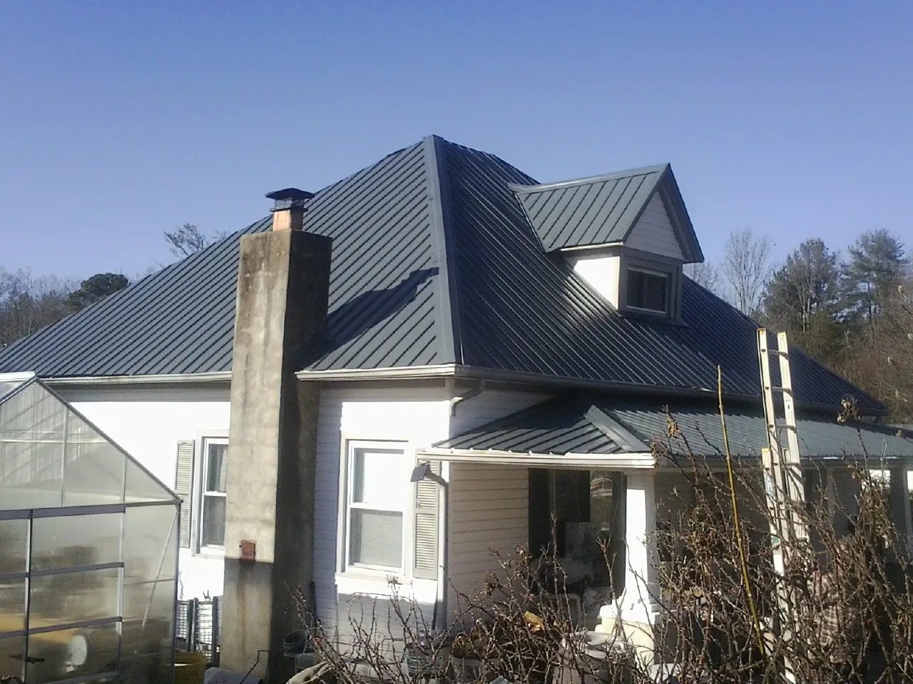 Dark blue standing seam metal roof on a white farmhouse with dormer — Slate & Tile Roof Repair by Roofing Brothers in Goldens Bridge