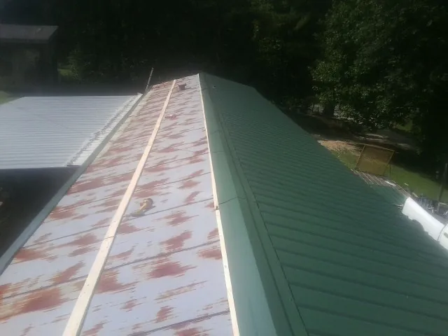Old rusted panels beside newly installed green metal roofing — Wind Damage Roof Repair by Roofing Brothers in Goldens Bridge