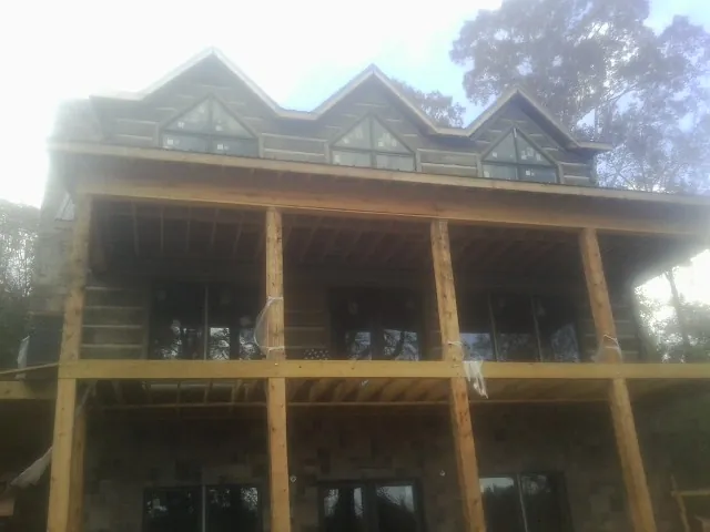 Dormers and porch framing on a large log home under construction — Roof Coating work by our crew in Goldens Bridge