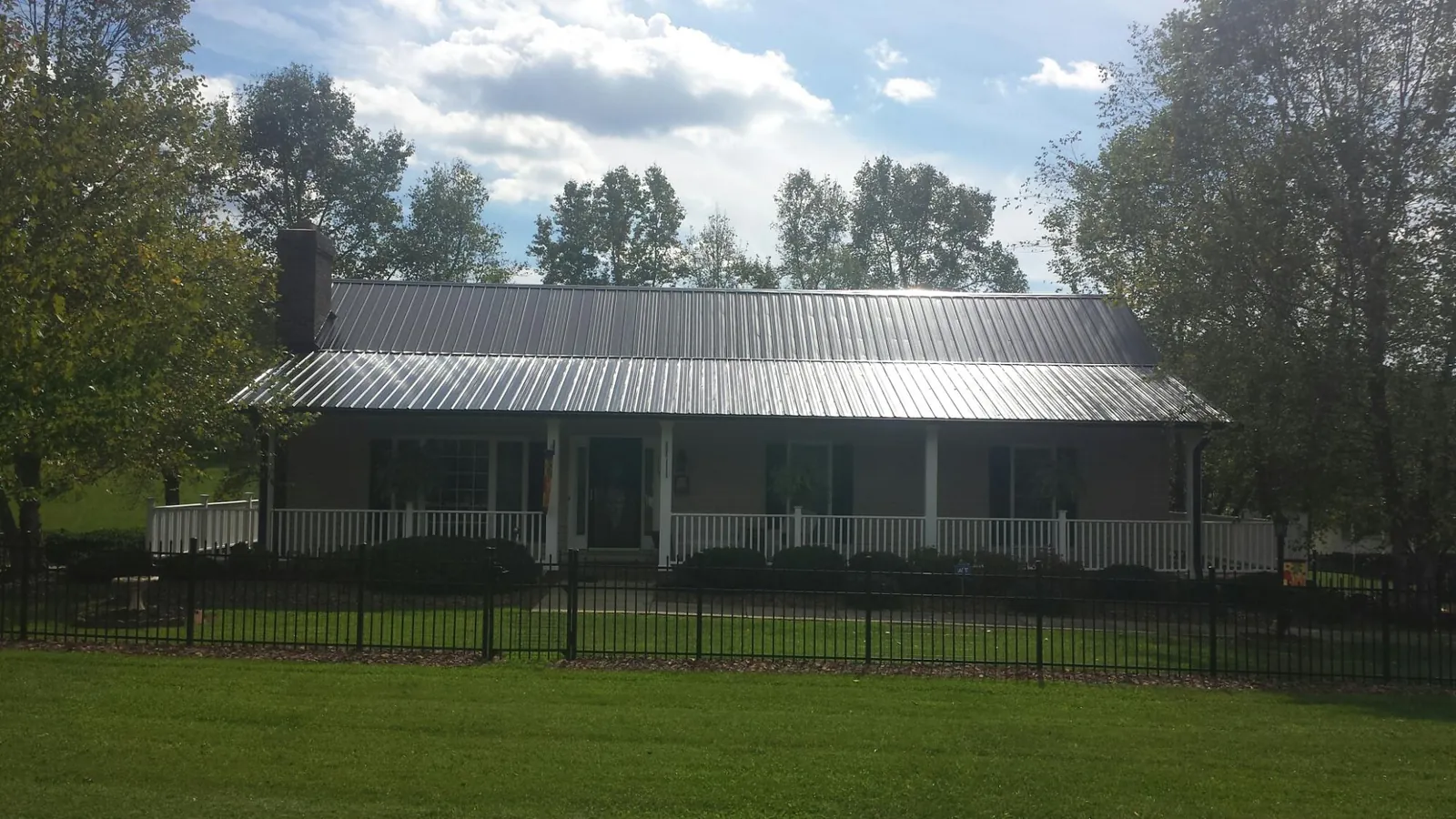 Gray metal roof on a brick ranch with a full width front porch — Gutter Guard Installation work by our crew in Goldens Bridge