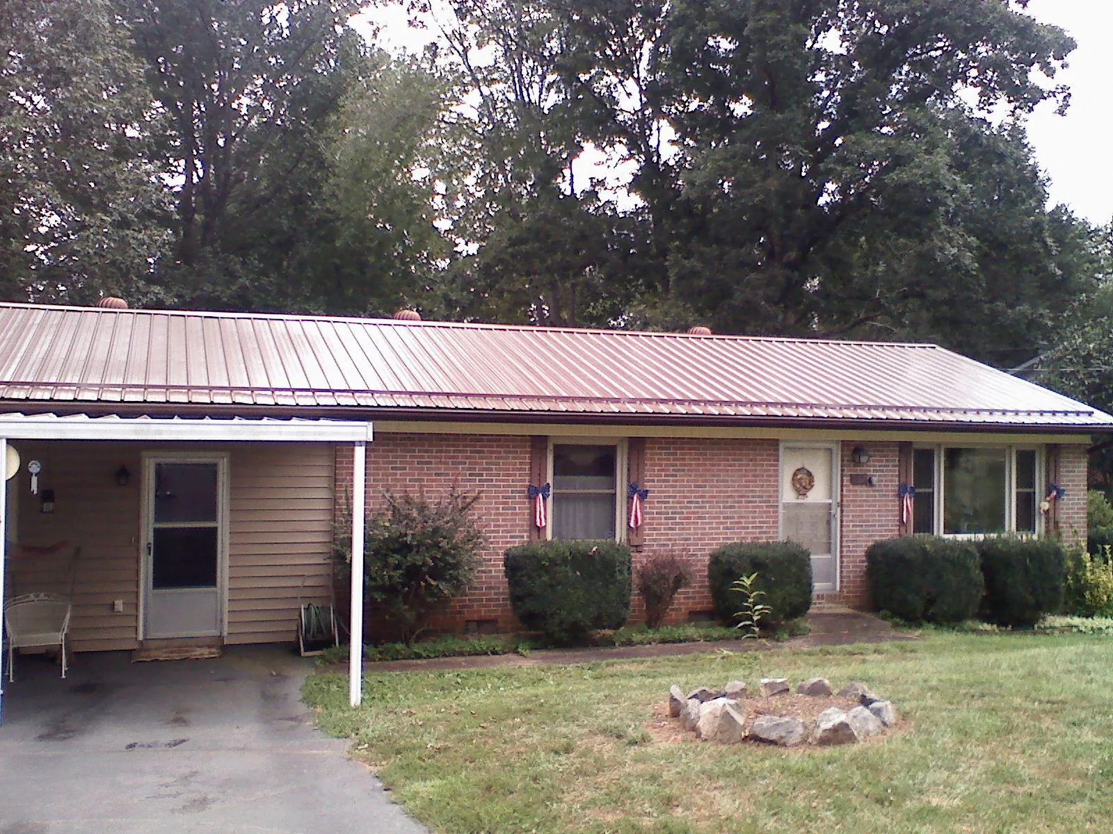 Bronze metal roof and carport on a brick ranch home — Roof Repair work by our crew in Goldens Bridge