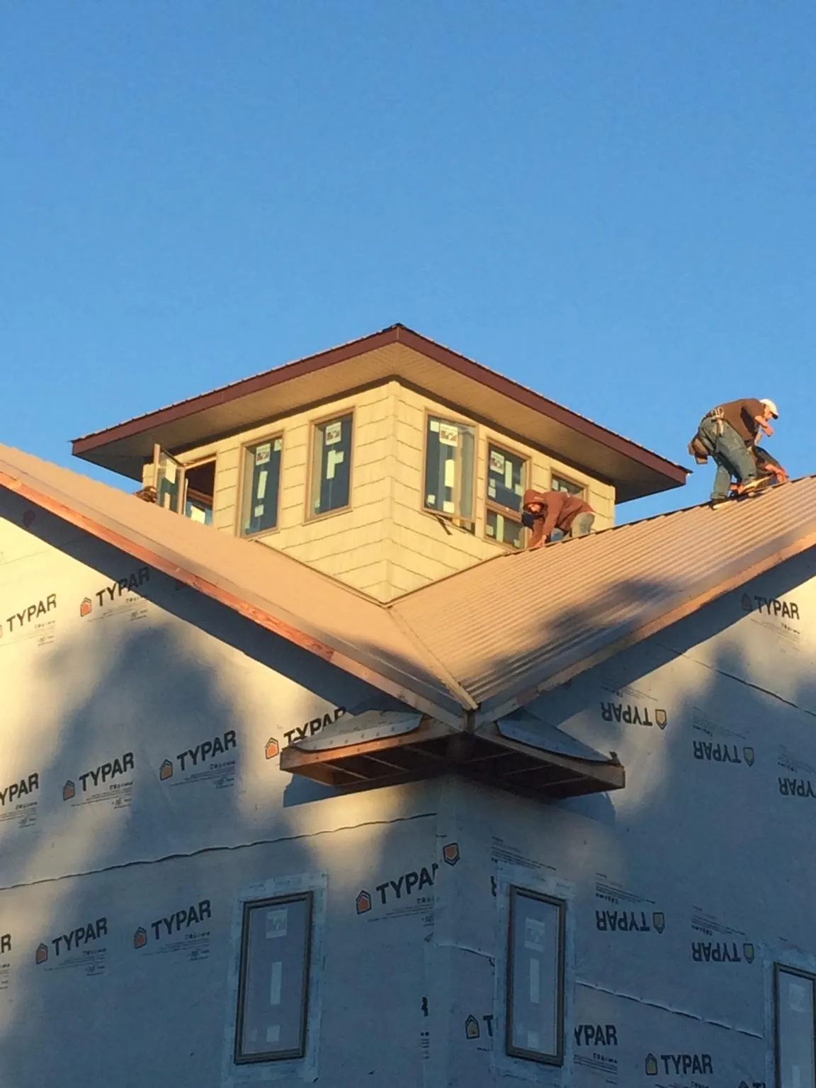 Roofers working around a rooftop cupola on a new metal roof at sunset — Roof Waterproofing in Goldens Bridge by Roofing Brothers